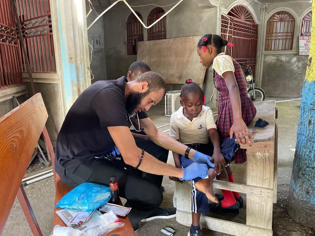 haitian doctor treating a wound on a child's leg